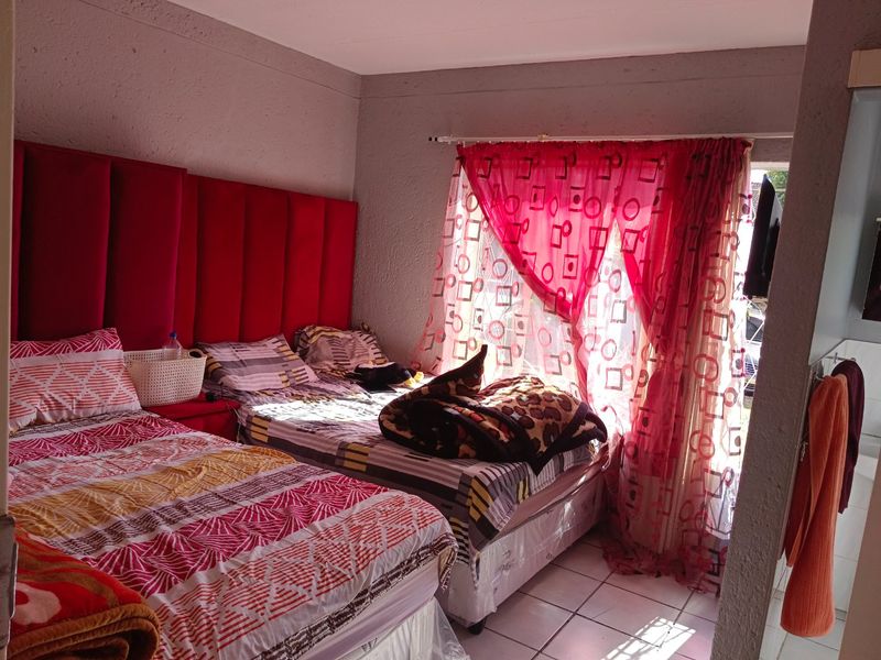 A bedroom featuring tiled flooring and a large window with curtain rod, providing natural light to the space.