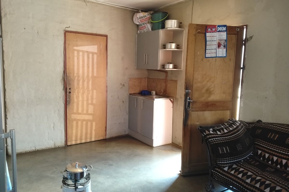 A basic kitchen area featuring compact cabinetry, a sink, and tiled splashback, requiring cosmetic updates to improve the overall finish and functionality.