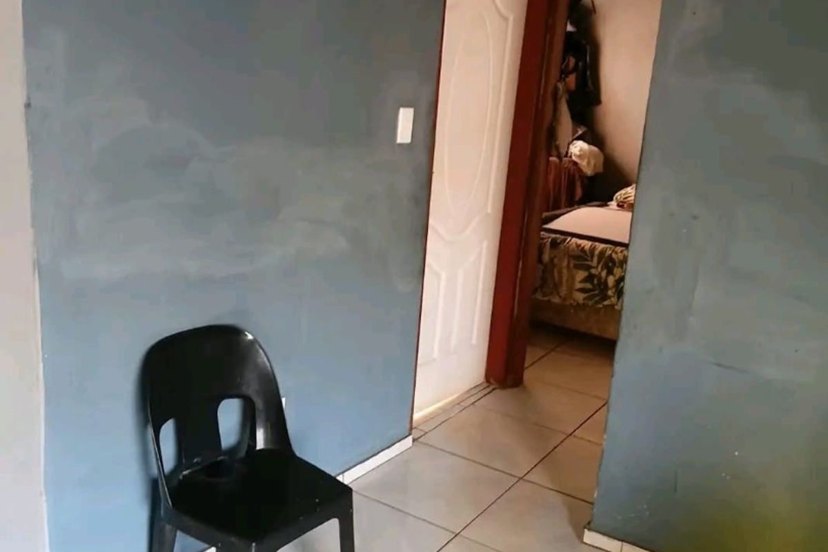 A hallway area featuring tiled flooring and access to an adjoining room, showing signs of wear on the wall surfaces.