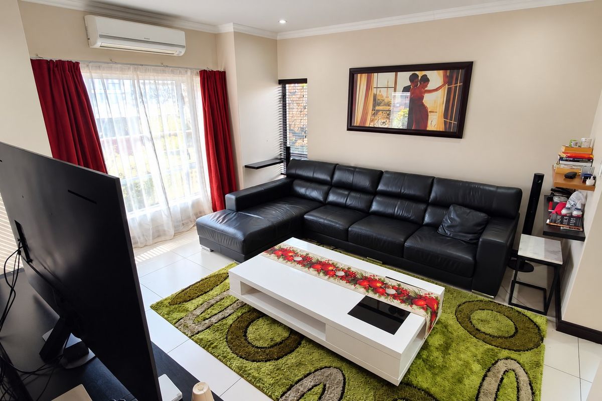 A well-maintained living room featuring tiled flooring, recessed downlighting, and a wall-mounted split-system air conditioning unit.