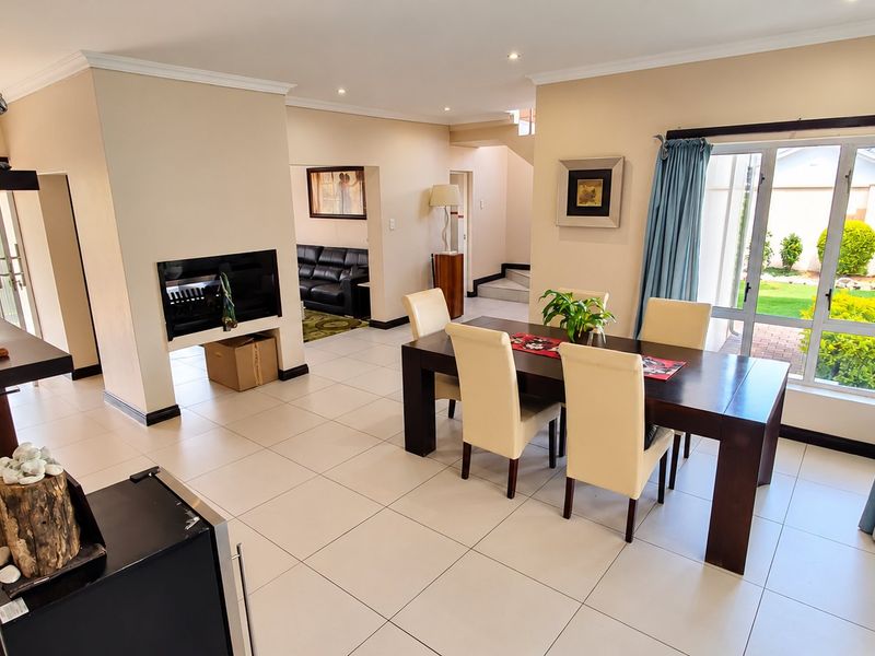 Spacious open-plan living and dining area featuring tiled floors, a built-in fireplace, and large sliding glass doors providing access to the garden.