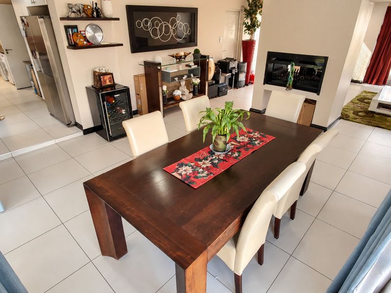 Spacious open-plan living and dining area featuring tiled flooring, a built-in fireplace, and a modern kitchen with ample cabinetry.