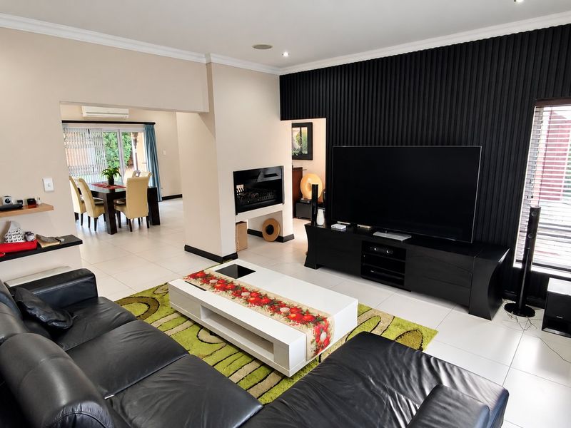 Spacious open-plan living area featuring a modern slatted feature wall, built-in fireplace, and large sliding doors leading to an adjacent dining space.