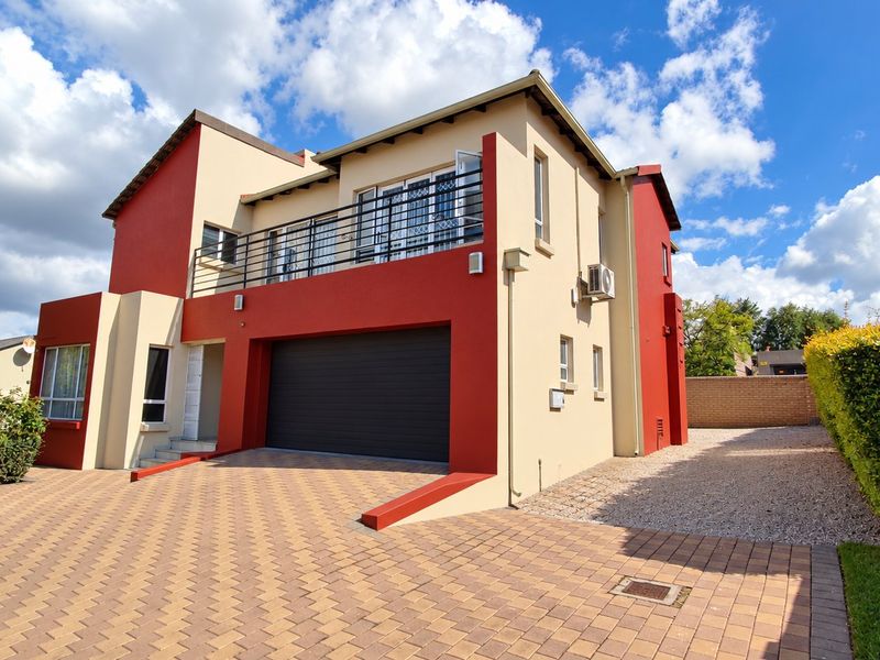Modern two-story residential property featuring a double garage, upper-level balcony with metal railing, and a paved driveway.