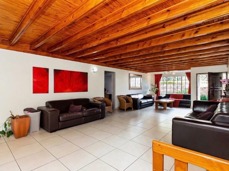 Spacious living area featuring a distinctive exposed timber beam ceiling and neutral tiled flooring, offering a bright and open layout with direct outdoor access.
