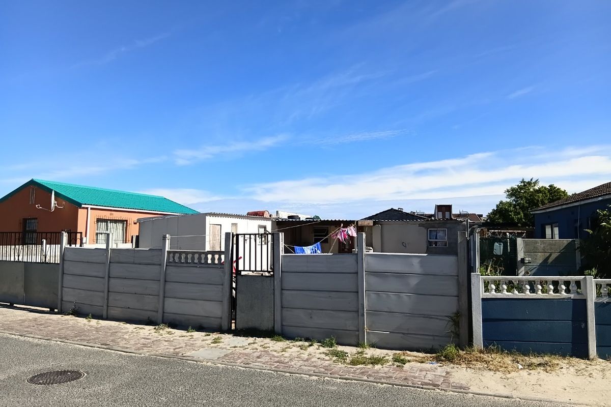 Front view of a residential property featuring a precast concrete boundary wall, metal gate, and paved street frontage.