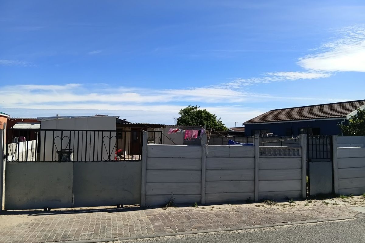 Front view of a residential property featuring a precast concrete boundary wall, metal sliding gate, and paved street-side verge.