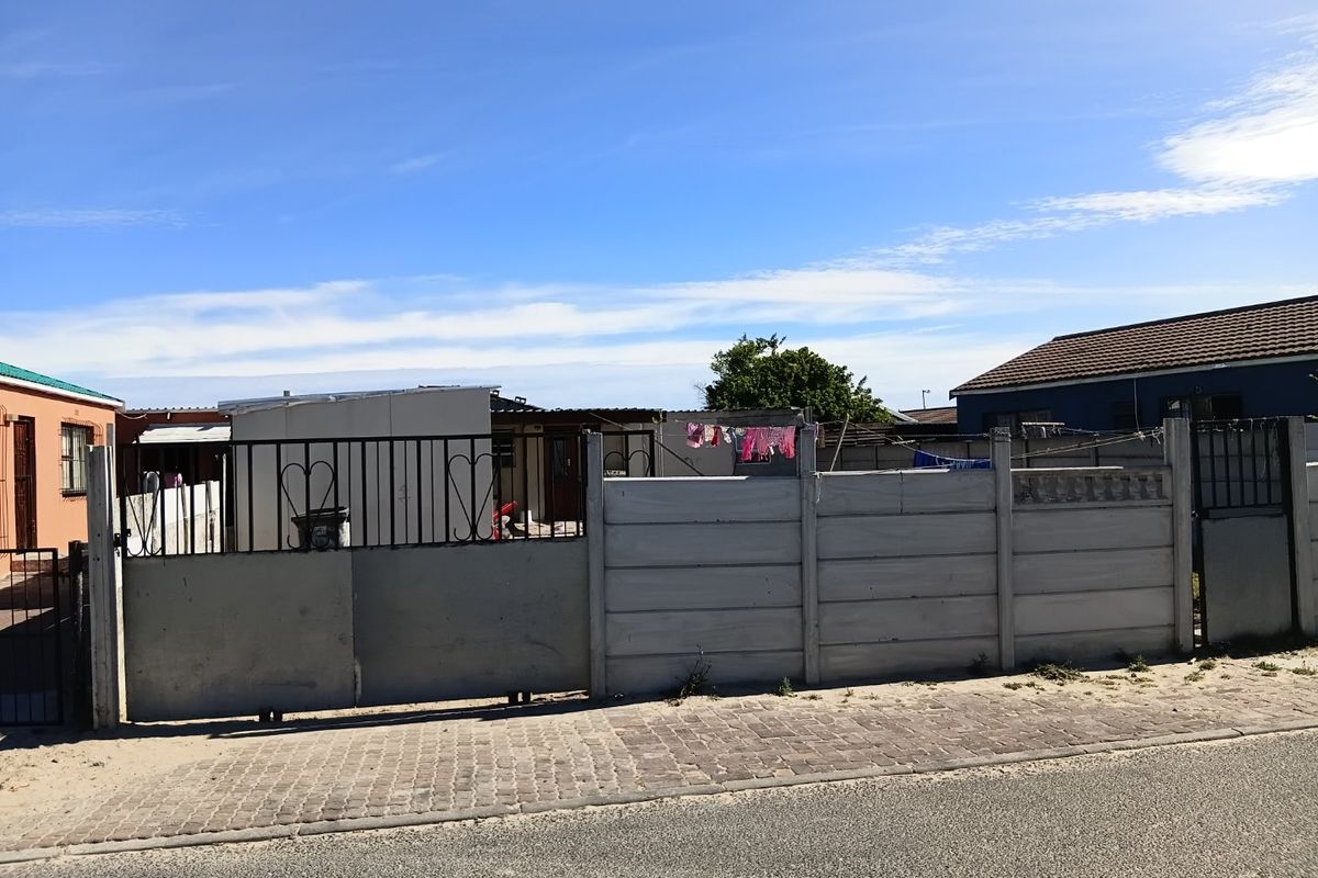 Front view of a residential property featuring a precast concrete boundary wall and metal sliding gate access from the street.