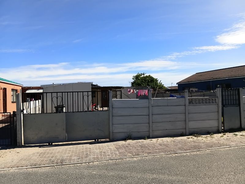 Front view of a residential property featuring a precast concrete boundary wall and metal sliding gate access from the street.