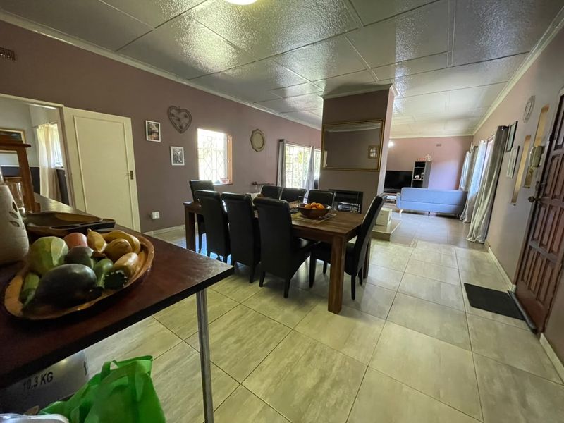 Spacious open-plan living and dining area featuring tiled flooring, a central fireplace, and neutral wall tones, offering a versatile layout for family living.