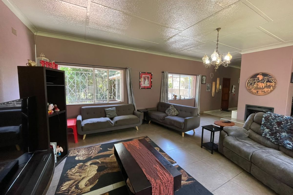 Spacious living room featuring tiled flooring, a built-in fireplace, and large windows with security bars, offering a comfortable and functional family space.