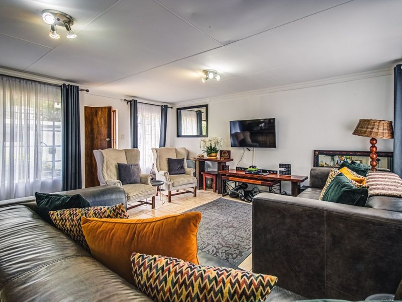 A comfortable living room featuring tiled flooring, ceiling spotlights, and large windows with sliding glass doors providing natural light.