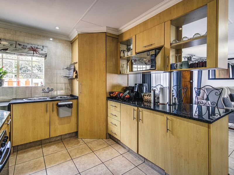 A functional kitchen featuring light wood cabinetry, granite countertops, tiled flooring, and a built-in microwave, offering a practical layout with ample storage space.