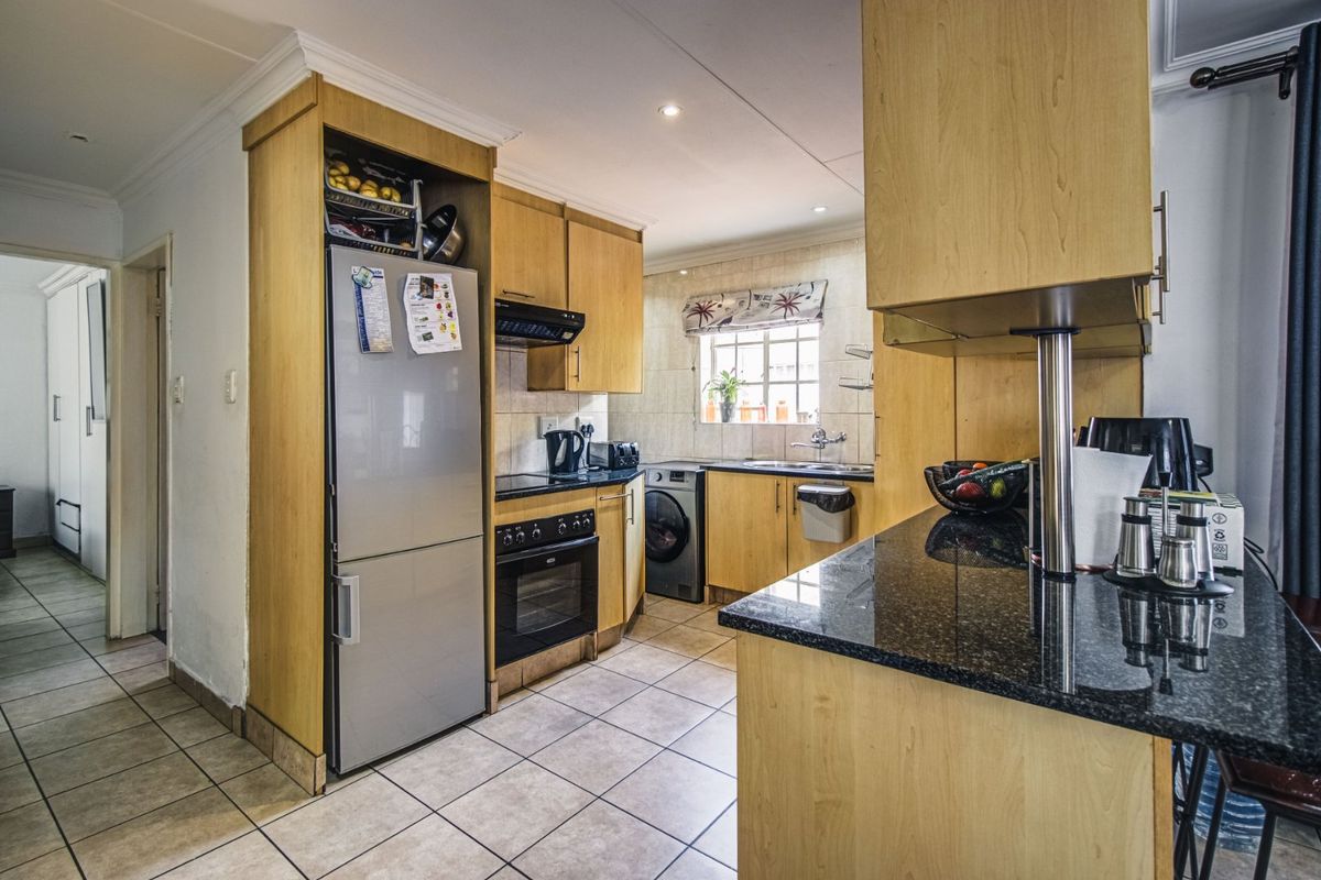 Functional kitchen featuring light wood cabinetry, granite countertops, built-in oven, hob, and tiled flooring with a practical layout.