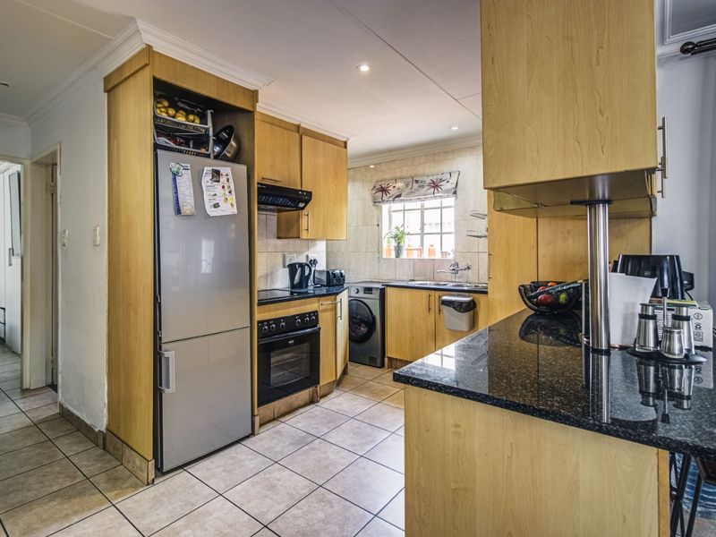 Functional kitchen featuring light wood cabinetry, granite countertops, built-in oven, hob, and tiled flooring with a practical layout.
