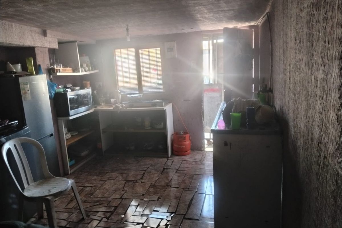A basic kitchen area featuring tiled flooring and built-in shelving, requiring significant renovation and finish work to improve functionality and aesthetic appeal.