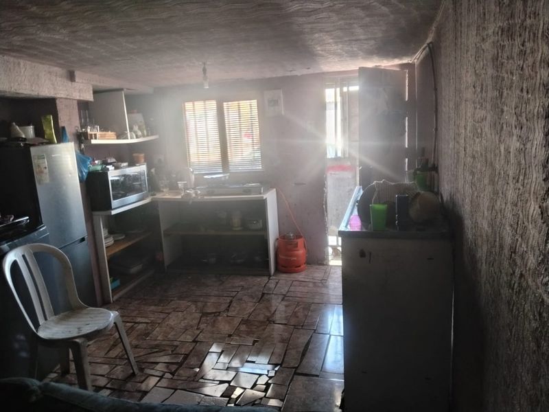 A basic kitchen area featuring tiled flooring and built-in shelving, requiring significant renovation and finish work to improve functionality and aesthetic appeal.
