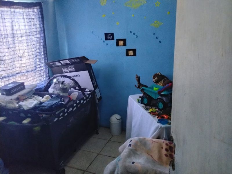 A bedroom featuring blue painted walls and tiled flooring, currently utilized as a nursery.