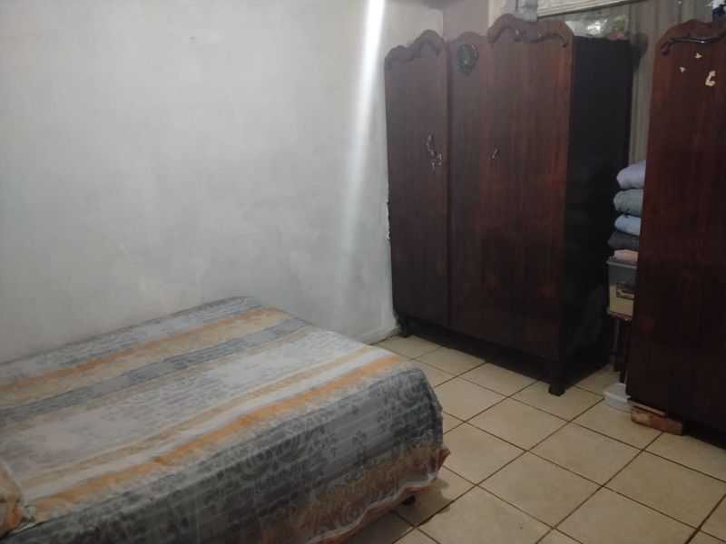 A bedroom featuring ceramic floor tiles and plain wall finishes, offering a basic space ready for cosmetic updates and modernization.