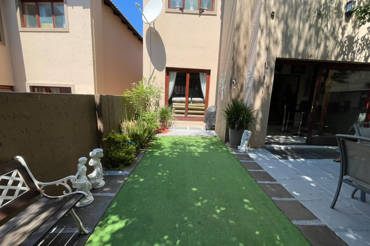 A private rear courtyard featuring artificial turf, a paved walkway, and direct access to the home through sliding glass doors.