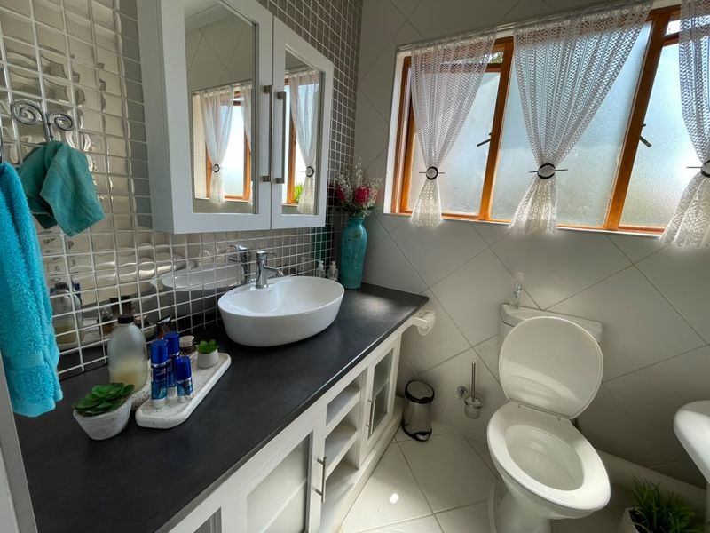 A well-maintained bathroom featuring a modern vessel sink, vanity cabinet with storage, mirror cabinet, and tiled finishes.