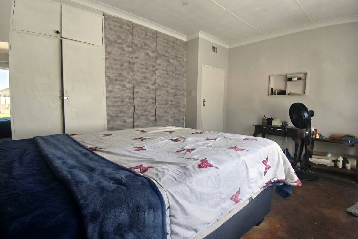 A bedroom featuring built-in cupboards, a coved ceiling, and a recessed wall shelf, with visible wear on the flooring.