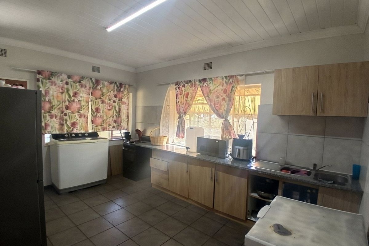 A functional kitchen featuring tiled flooring, built-in cabinetry, and a double sink, offering potential for modernization and layout optimization.