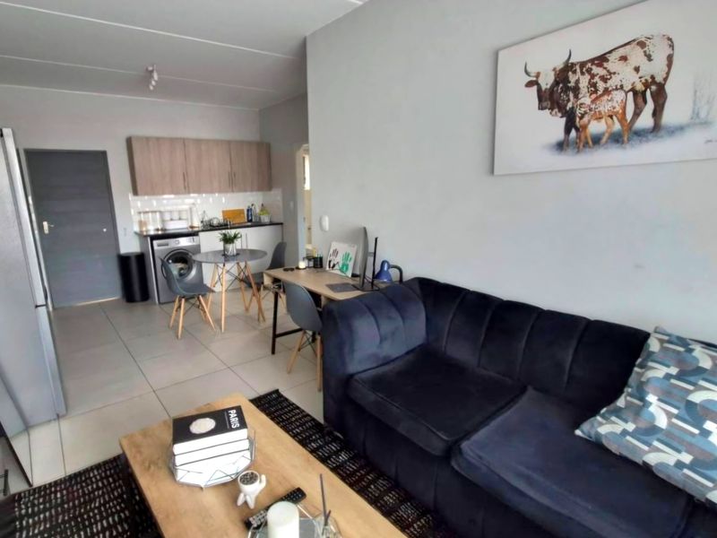 An open-plan living and kitchen area featuring tiled flooring, modern cabinetry, and a functional layout suitable for compact apartment living.