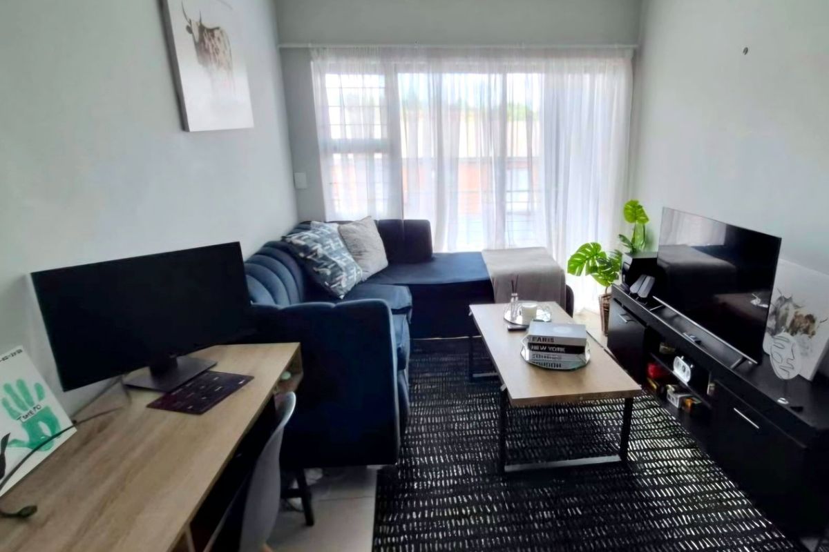 A compact living room featuring tiled flooring and a large window that allows for natural light.