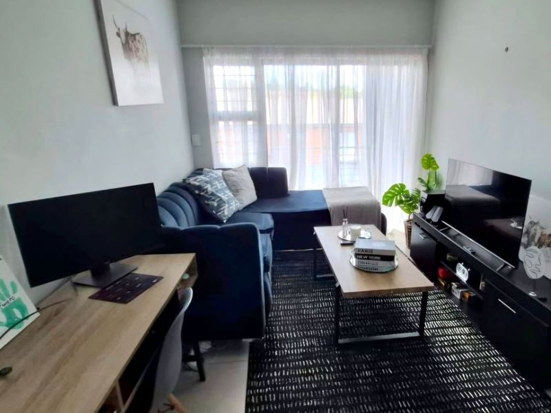 A compact living room featuring tiled flooring and a large window that allows for natural light.