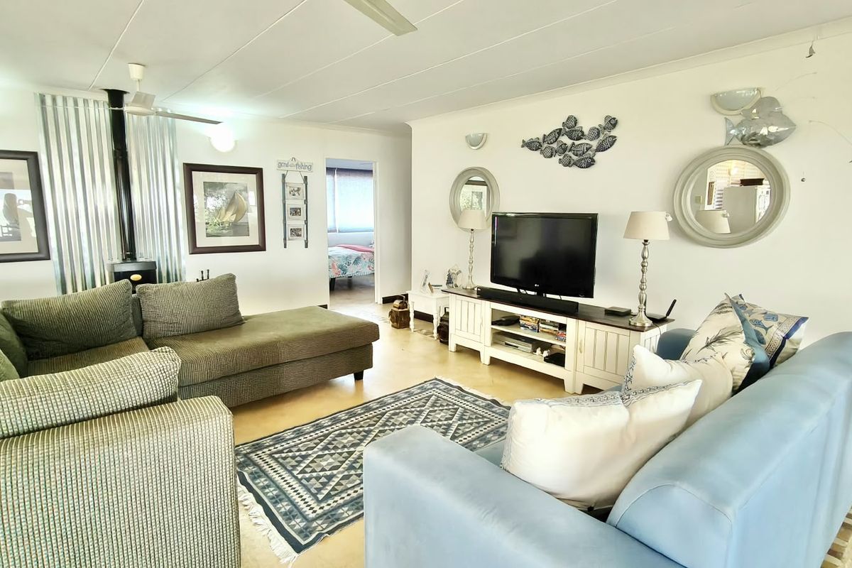Spacious living room featuring a wood-burning fireplace, ceiling fan, and tiled flooring, offering a comfortable and functional layout.