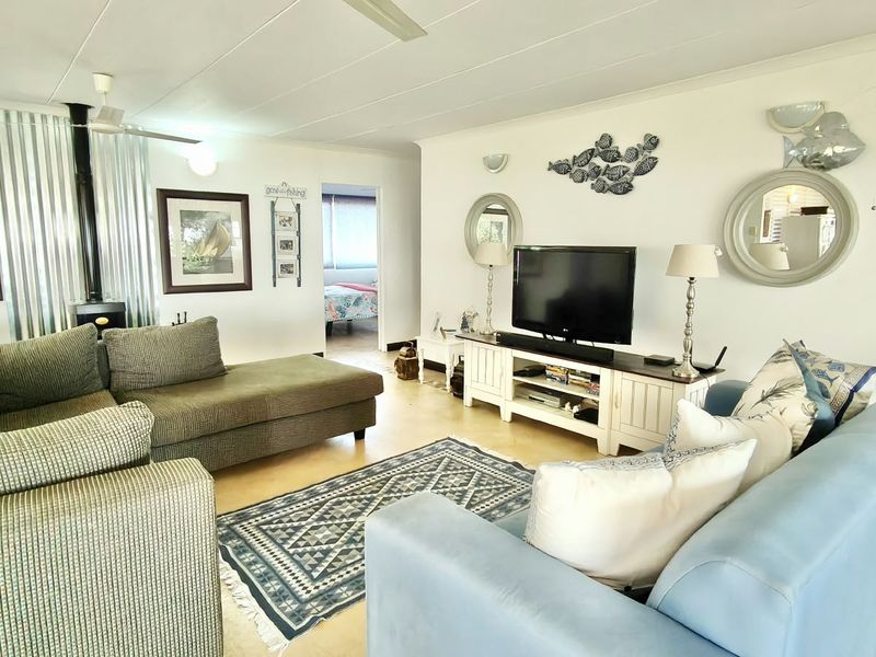 Spacious living room featuring a wood-burning fireplace, ceiling fan, and tiled flooring, offering a comfortable and functional layout.