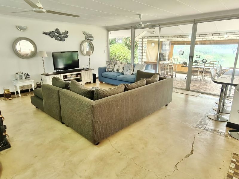 Spacious open-plan living area featuring polished concrete floors, a wood-burning stove, and large sliding glass doors providing seamless access to the outdoor patio.