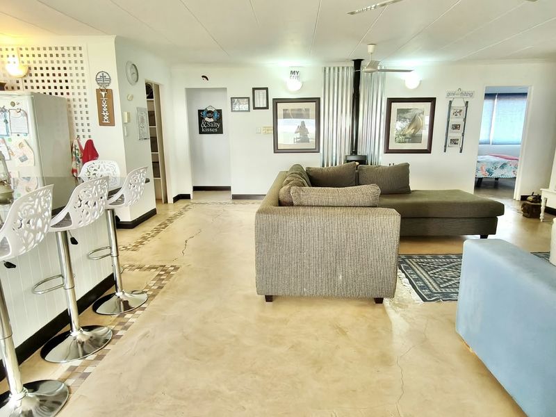 Spacious open-plan living area featuring polished concrete floors, a wood-burning stove, and a breakfast bar, offering a versatile layout for modern living.