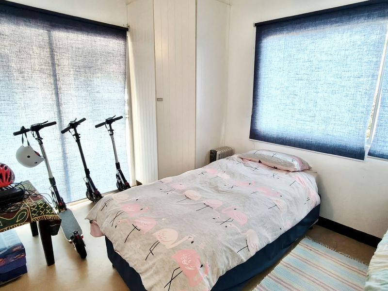A functional bedroom featuring built-in cupboards and roller blinds, providing essential storage and light control.