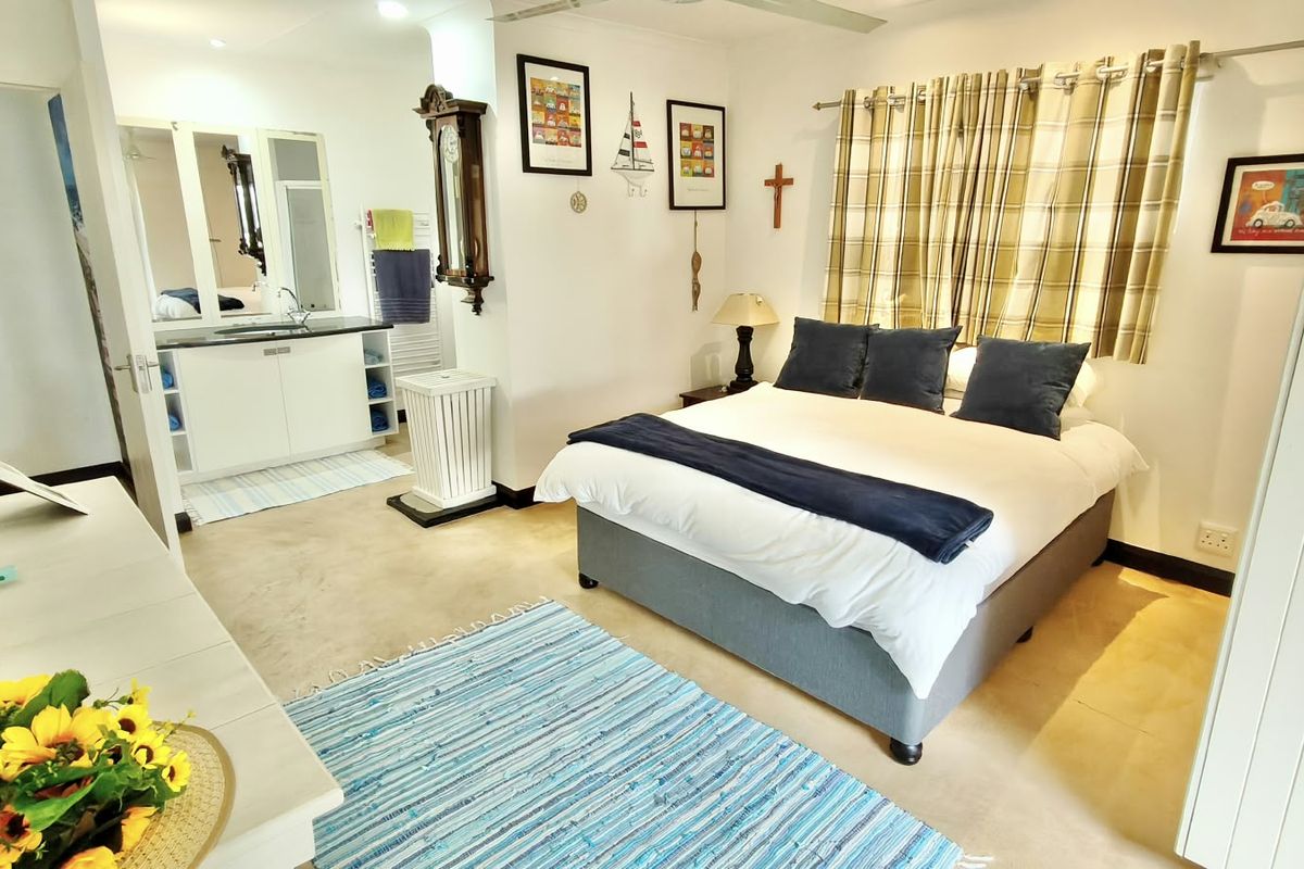 A well-maintained bedroom featuring an open-plan en-suite bathroom with a vanity unit and neutral tiled flooring throughout.