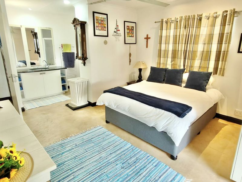 A well-maintained bedroom featuring an open-plan en-suite bathroom with a vanity unit and neutral tiled flooring throughout.