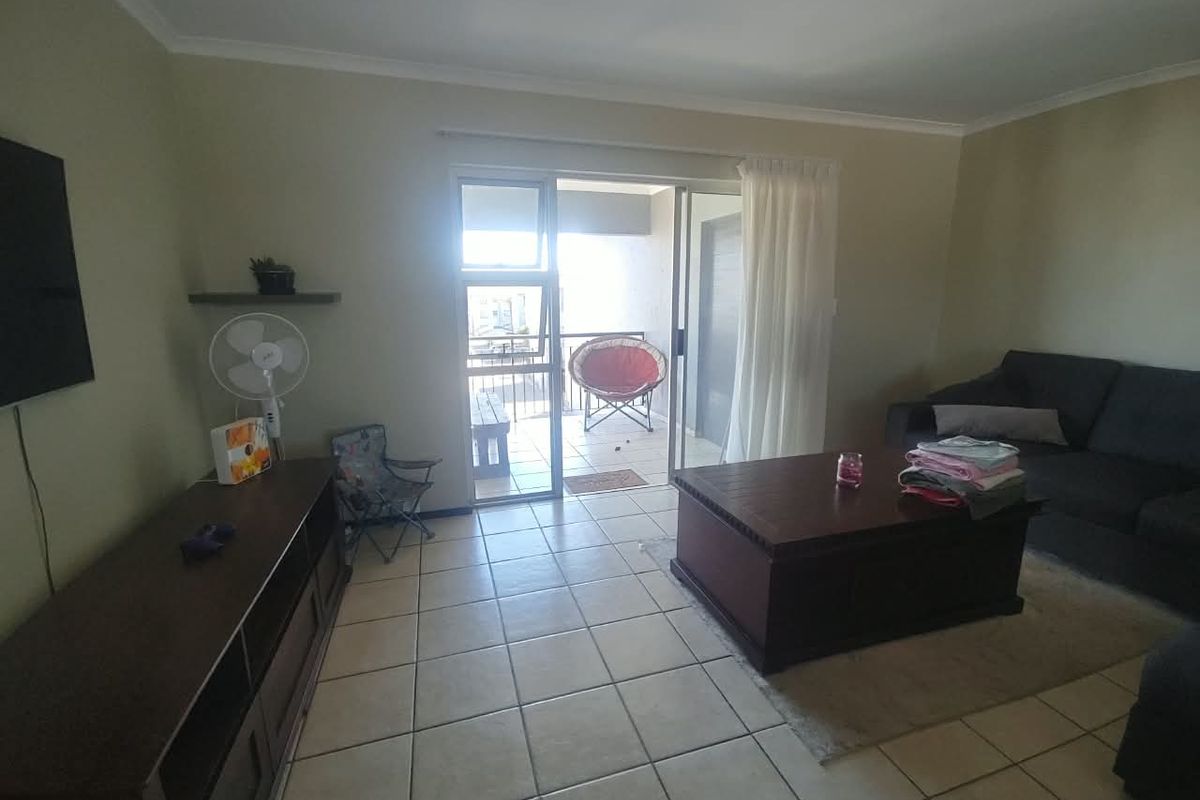 A living room featuring tiled flooring and a sliding glass door providing access to an attached balcony.