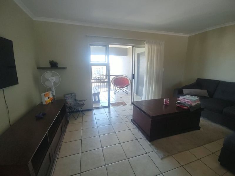 A living room featuring tiled flooring and a sliding glass door providing access to an attached balcony.