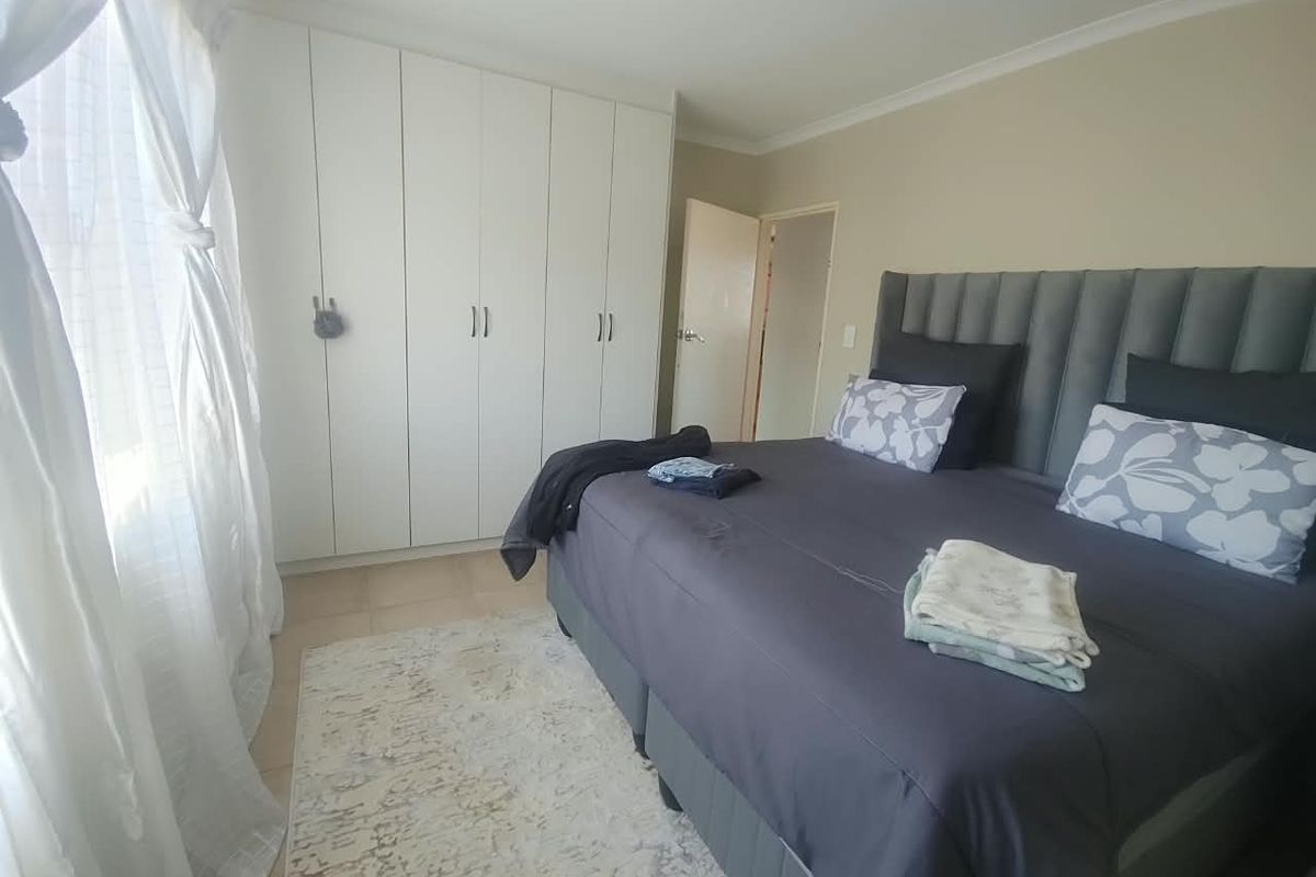 A well-maintained bedroom featuring neutral wall tones, tiled flooring, and ample built-in cupboard storage space.