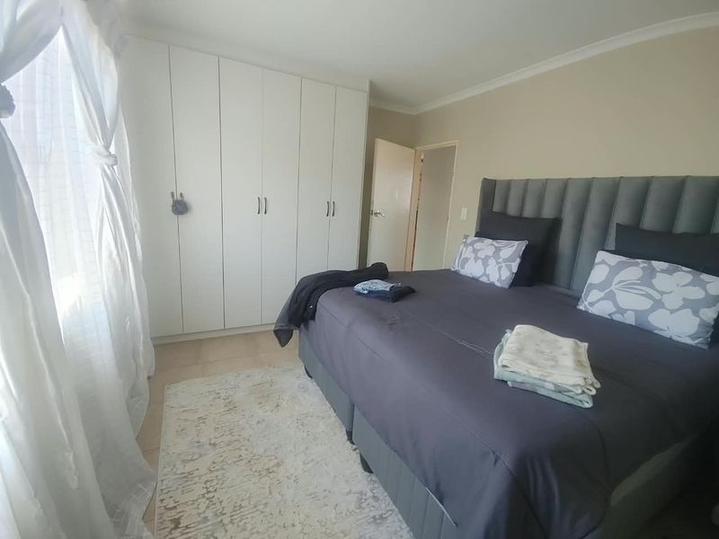 A well-maintained bedroom featuring neutral wall tones, tiled flooring, and ample built-in cupboard storage space.