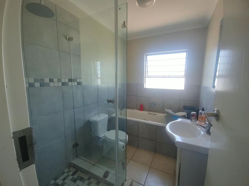 A functional bathroom featuring a glass-enclosed shower, a built-in bathtub, a pedestal basin, and tiled finishes throughout.