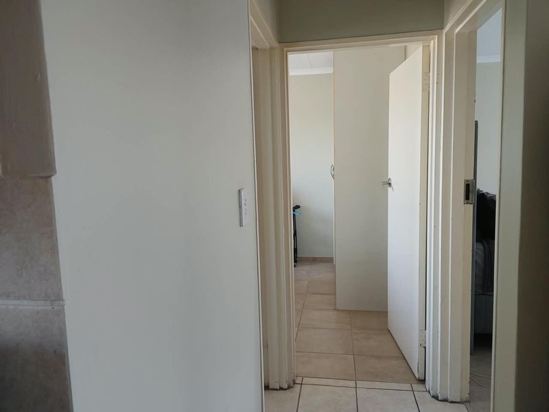 A functional hallway connecting multiple rooms, featuring neutral tiled flooring and standard internal door frames.