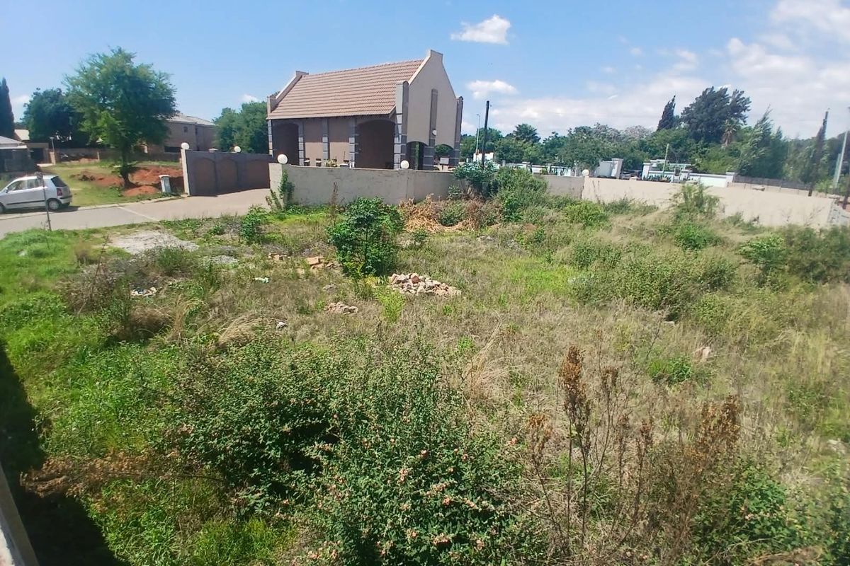 A vacant residential plot featuring overgrown vegetation and perimeter walling, offering a blank canvas for future development in a established neighborhood.
