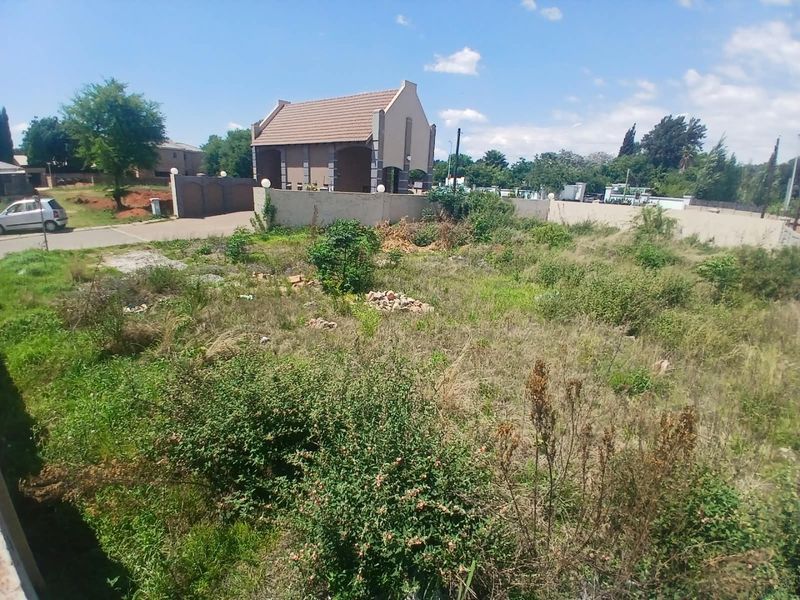 A vacant residential plot featuring overgrown vegetation and perimeter walling, offering a blank canvas for future development in a established neighborhood.