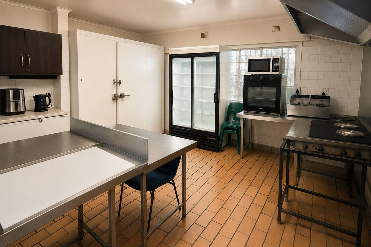 Commercial kitchen facility featuring stainless steel prep surfaces, built-in cold storage, commercial-grade oven, extractor hood, and durable tiled flooring.