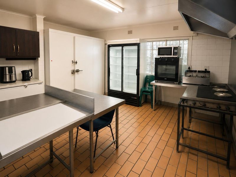 Commercial kitchen facility featuring stainless steel prep surfaces, built-in cold storage, commercial-grade oven, extractor hood, and durable tiled flooring.