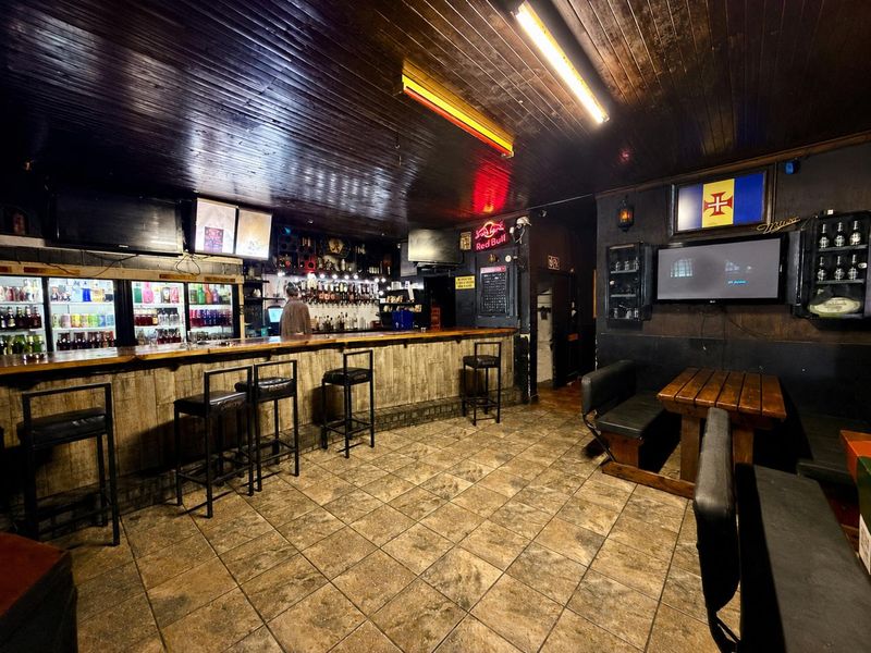 A commercial bar area featuring a built-in service counter, timber-paneled ceiling, and tiled flooring, suitable for hospitality or entertainment use.