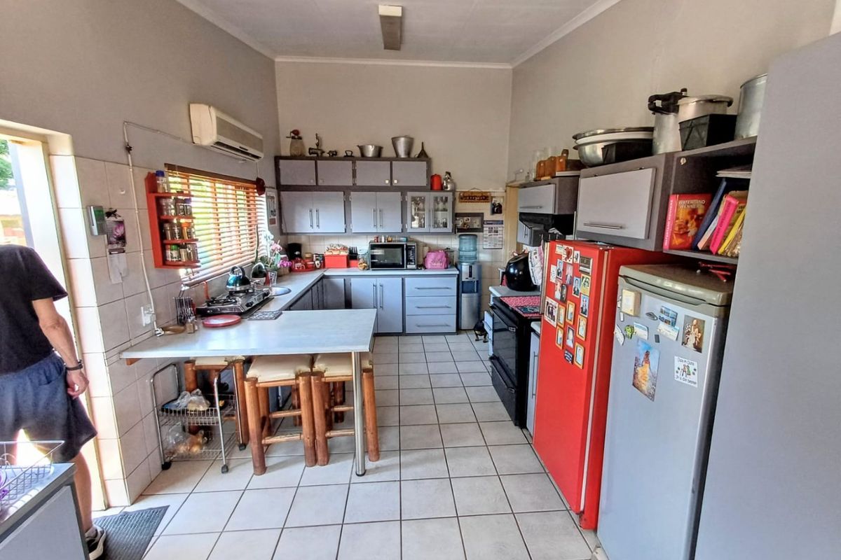 A functional kitchen featuring tiled flooring, built-in cabinetry, a breakfast counter, and an integrated air conditioning unit, offering potential for modern updates.