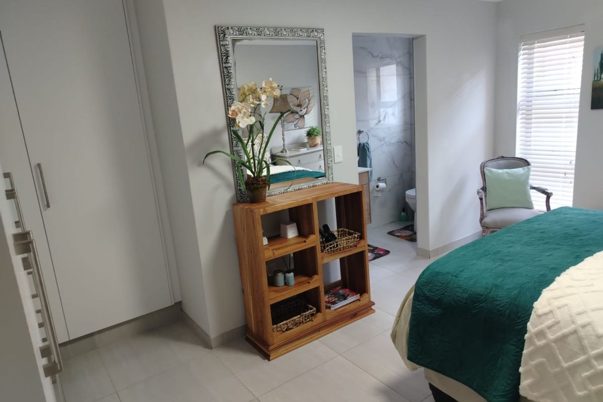 A well-maintained bedroom featuring tiled flooring, built-in cupboards, and direct access to an en-suite bathroom with modern finishes.